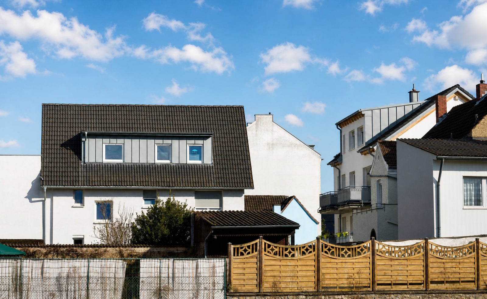 Dieselben Häuser vor blauem Himmel mit einzelnen Wolken.
